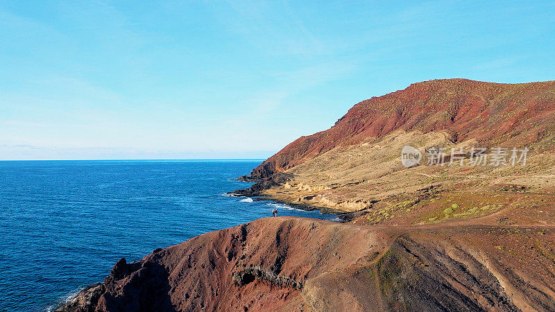 Aerial view of a hikers looking to the volcanic cone of Montaña Roja in El Medano, Tenerife Islands